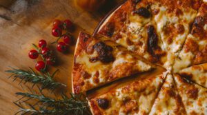 imagen de fondo con pizza sobre tabla de madera y tomates cherry