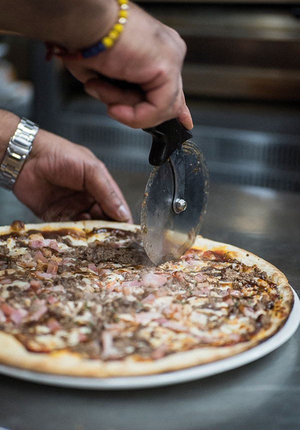 Cocinero cortando pizza