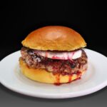 Hamburguesa Piazzetta, Jamón serrano, queso de cabra, cebolla caramelizada, salsa miel y mosataza, mermelada de frambuesa