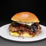 Hamburguesa burrata, 2 bolas de carne madurada 100 gr cada una, queso burrata, mozzarella, mortadela italiana, tomate cherry confitado, brotes, pistachos picados y salsa de pesto